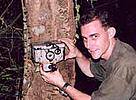 Barney Long rigging a camera trap in the forest.