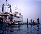 A large Spnaish trawler floats in stark contrast to the local fishermen's boat, Senegal.
