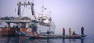Artisanal pirogue with local fishermen passing Spanish trawler in their fishing grounds. Senegal. / ©: WWF-Canon / Jo BENN / ©: WWF-Canon / Jo BENN