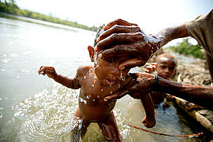 Bathing a young child in the April River, Pukapuki village.